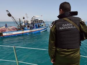 A member of the Tunisian Coast Guard observes a fishing boat. (AFP/File)