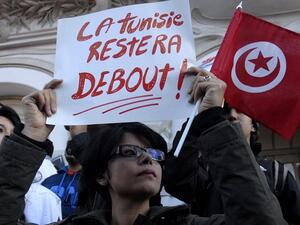 A Tunisian woman holds a placard reading in French "Tunisia will remain standing" as she takes part in a protest on March 18, 2015 after an attack on the Bardo National Museum in Tunis. (Sofiene Hamdaoui/ AFP)