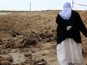 A Yazidi woman stands next to an unearthed mass grave in northern Iraq (Safin Hamed/AFP)
