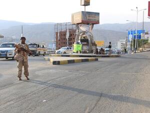 A picture taken on May 3, 2016 shows a Yemeni security forces member patrolling a street with a banner hung by Al-Qaeda militants in the Yemeni port of Mukalla, 300 miles east of Aden. (AFP/Stringer)