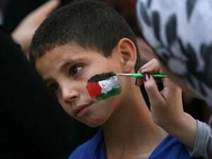 متظاهرة يمنية ترسم علم فلسطين على وجه احد الأطفال المشاركين