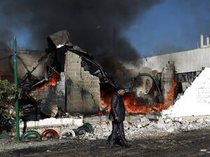 A Yemeni man walks past flames rising from the ruins of buildings destroyed in an air-strike by the Saudi-led coalition on February 10, 2016 in the capital Sanaa. (AFP/Mohammed Huwais)