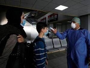 عامل في المجال الصحي يفحص المسافرين في مطار دمشق الدولي