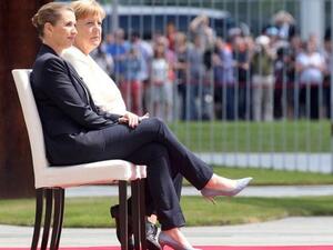 ميركل المرتجفة تجلس على كرسي أثناء عزف النشيد الوطني