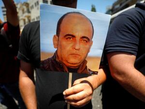 متظاهر يحمل صورة نزار بنات خلال احتجاج في رام الله