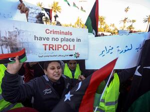 A Libyan youth holds up a protest sign during a demonstration against strongman Khalifa Haftar in the capital Tripoli's Martyrs Square on April 12, 2019.  Mahmud TURKIA / AFP