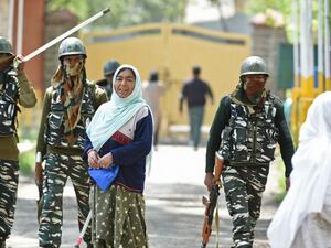 Indian paramilitary troopers patrol as a Kashmiri woman voter looks on in Srinagar  (AFP)