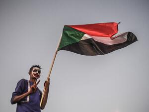 A Sudanese protestor waves a national flag during a protest  (AFP)