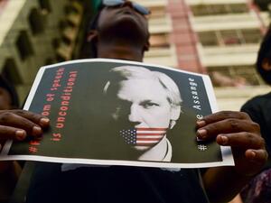 An activist holds a placard next to others while forming a human chain calling for the freedom of the international non-profit organisation"WikiLeaks" founder Julian Assange (AFP)