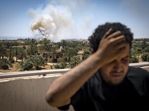 A fighter loyal to the internationally-recognised Government of National Accord (GNA) stands on a rooftop as smoke rises in the distance during clashes with forces loyal to strongman Khalifa Haftar (AFP)