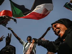 Sudanese protesters chant slogans and wave the national flag during a sit-in outside the army headquarters in the capital Khartoum  (AFP)