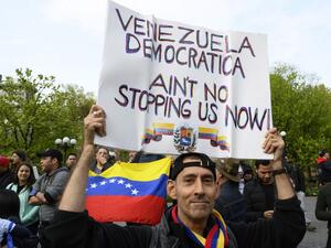 A man holds a sign as protesters gather at Union Square Park, in support of Venezuela's Operation Freedom and the Venezuelan opposition (AFP)