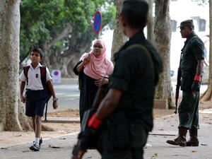 Sri Lankan security personnel stand guard as a school student (L) returns to classes as schools re-open across the country after the Easter attacks in Colombo (AFP)