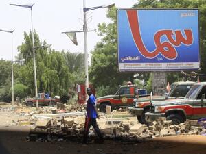A man crosses a street as vehicles belonging to members of Sudan's paramilitary Rapid Support Forces are lined up in Khartoum's Nile street in the capital   (AFP)