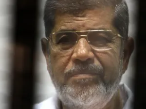 Egyptian ousted Islamist president Mohamed Morsi looks on from behind the defendants cage during is trial alongside 130 others on charges of organising jail breaks during the 2011 uprising that toppled strongman Hosni Mubarak (AFP)