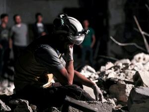 A member of the Syrian Civil Defence, also known as the "White Helmets", reacts as his comrades clear debris while searching for bodies or survivors in a collapsed building following a reported government air strike in the village of Saraqib in Syria's northwestern Idlib province  (AFP)