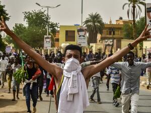 A Sudanese protester covering his face with a jersey flashes the victory gesture while marching with others in a mass demonstration against the country's ruling generals in the capital Khartoum's twin city of Omdurman on June 30, 2019.  Ahmed MUSTAFA / AFP