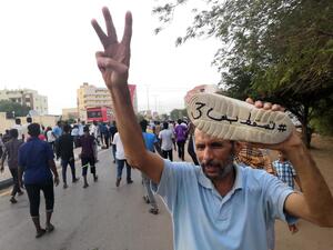A Sudanese protester flashes the gesture for the number three as he raises a shoe painted with the Arabic words "#JustFall3" during a mass demonstration against the country's ruling generals in the capital Khartoum on June 30, 2019.  AFP