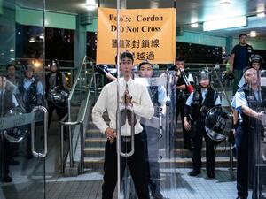 A security guard (C) closes the door of the shopping arcade as riot police stand guard at a footbridge during an anti-parallel trading protest in Sheung Shui district in Hong Kong  (AFP)