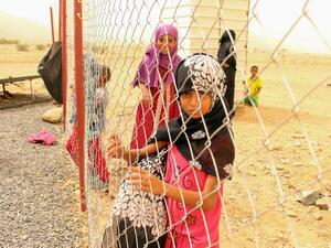 A displaced Yemeni girl looks on from a wire fence at a make-shift camp in the country's northern Hajjah province  (AFP)