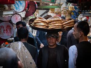 A trader carries a tray of bread on his head through one of the packed local markets in Kabul. Thijs said: 'People are going to their work and trying to get by and not sit around and feel miserable and mope all day about their situation'  (dailymail.co.uk/Thijs Broekkamp)