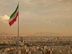 Iran flag waving in the wind above skyline of Tehran (Shutterstock)	