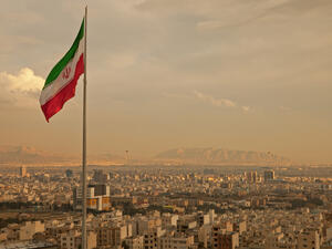 Iran flag waving in the wind above skyline of Tehran (Shutterstock)	