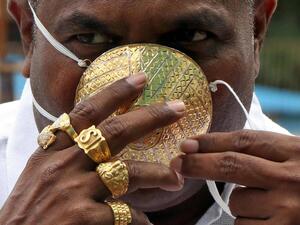 يضع رجل هندي كمامة مصنوعة من الذهب