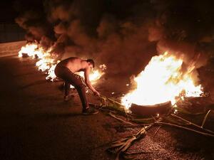 متظاهر لبناني مناهض للحكومة يحرق إطارات لسد الطريق السريع الساحلي شمال العاصمة بيروت
