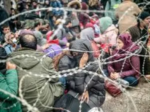 Migrants behind barbed wire fence in buffer zone along Turkey-Greece border /AFP