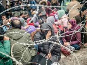 Migrants behind barbed wire fence in buffer zone along Turkey-Greece border /AFP