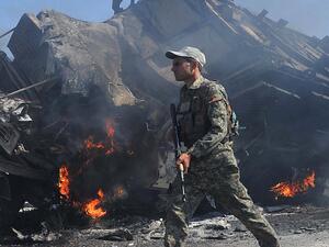 جندي أفغاني قرب عربة عسكرية محترقة