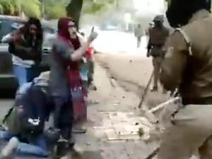 The video shows several police officers in riot gear hitting a man with sticks and dragging him to the ground. 