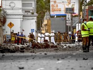 Sri Lankan priests look at the debris of a car after it explodes when police tried to defuse a bomb near St. Anthony's Shrine in Colombo on April 22, 2019. (AFP)