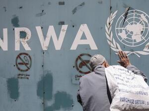 A Palestinian man stands in front of the emblem of the UN Relief and Works Agency for Palestine Refugees in the Near East (UNRWA) outside the agency's offices in Gaza City, July 31, 2018. (AFP/ File Photo)