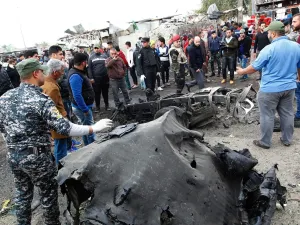 Security forces and civilians surround a destroyed car at the site of Monday's bombing. ( SABAH ARAR/Getty-AFP )