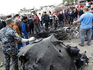 Security forces and civilians surround a destroyed car at the site of Monday's bombing. ( SABAH ARAR/Getty-AFP )