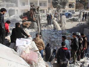 Syrian men and civil defense volunteers search for survivors amid the rubble of a building following airstrike on the northwestern city of Idlib. (AFP)