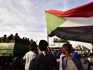 Sudanese demonstrators gather as an army vehicle drives by, near the military headquarters in the capital Khartoum on April 14, 2019. (AFP)