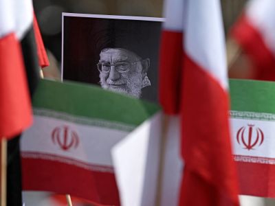 A protestor holds a placard with an image of the late Iranian Supreme Leader Ayatollah Ali Khamenei surrounded by Iranian flags outside the US consulate during a protest against the conflict in the Middle East in Mexico City on March 7, 2026. (Photo by Carl de Souza / AFP)