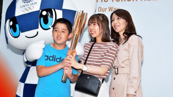 Visitors pose for a photo with a torch of the Tokyo 2020 Olympic Games during a news conference on the torch relay Saturday in Tokyo, Japan. Photo by Keizo Mori/UPI