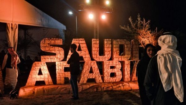 People stand before a sign showing the logo of the Dakar Saudi Arabia 2020 rally, during a press conference about the event in Qiddiya.