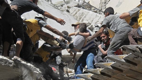 White Helmet rescue volunteers and civilians rescue a child from the rubble of a building destroyed during an air strike by Syrian regime forces and their allies on the town of Ariha, in the southern outskirts of Syria's Idlib province on May 27, 2019. (Amer ALHAMWE / AFP)