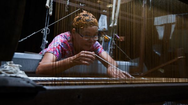 This photo taken on May 22, 2019 shows Rampai Sripetch, a 65-year-old Thai Muslim woman, weaving silk fabric on a loom at a workshop near Darul Falah mosque in Bangkok. (Romeo GACAD / AFP)