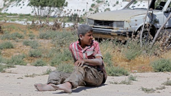 A young Syrian man sits on the ground after a bombing on an industrial area of Idlib, Northern Syria, on June 18, 2019. (AFP/ File Photo)