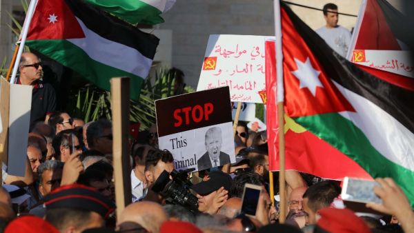 Protesters hold an anti-Donald Trump signs and Jordanian flags during the "March of Anger" demonstration leading to the US embassy headquarters in the Jordanian capital Amman on June 21, 2019, against the US President's "Deal of the Century" and the US-led Middle East economic conference in Bahrain. (Khalil MAZRAAWI / AFP)