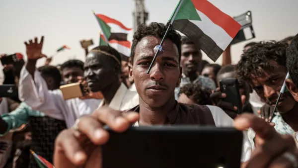 A man poses for a "selfie" photo with a cell phone while having a miniature Sudanese flag placed on his forehead with a plastic suction cap as he awaits the arrival of the deputy head of Sudan's ruling Transitional Military Council. (AFP/ File Photo)