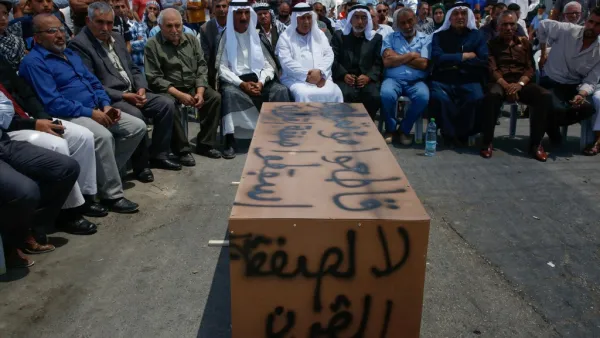 Palestinian men sit around a makeshift coffin with the words "No to the deal of the century", during a protest against a US-led meeting this week in Bahrain on the Palestinian-Israeli conflict, in the village of Yatta near the West Bank city of Hebron, on June 24, 2019. (AFP/ File Photo)