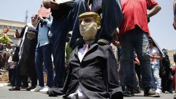 Palestinian demonstrators step on an effigy of US President Donald Trump during a protest against the US-sponsored Middle East economic conference that opens today in Bahrain, in the Israeli-occupied West Bank city of Nablus on June 25, 2019. (AFP/ File Photo)