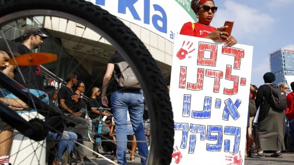 A woman holds a banner reading in Hebrew "our children blood is not lawlessness" as Israelis of Ethiopian origin protest on July 8, 2019 in Tel Aviv after the death of a young man of Ethiopian origin who was killed by an off duty police officer in Kiryat Haim. (AFP/ File Photo)